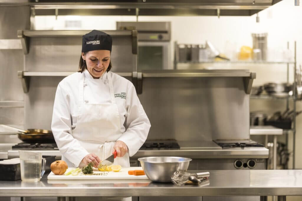 Female student in culinary lap chopping vegetables