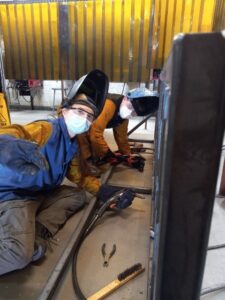 Students Bailey Schlievert and Nick Dufresne are shown in welding gear building bike racks.