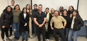 Group of public relations students standing with Graham Spero in a classroom