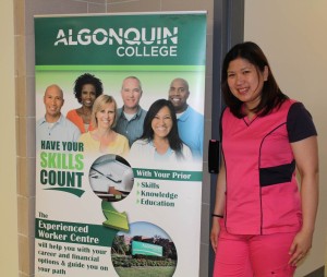 Norrie Lynn poses beside an Algonquin College banner in her scrubs.