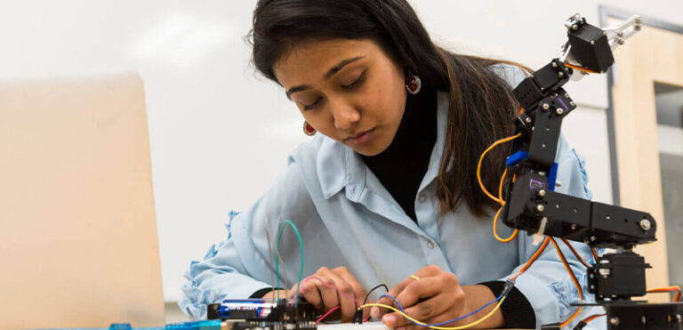 female student connecting wires on a switchboard