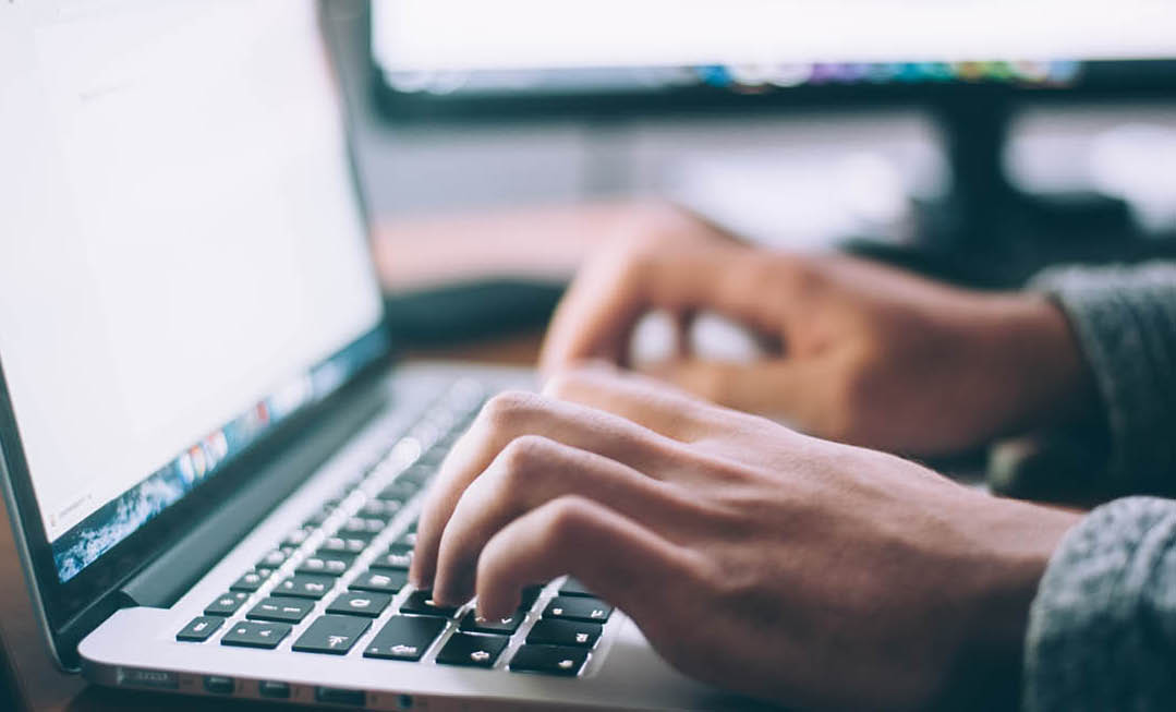 Close-up photo of someone's hands on a laptop with a bright screen. 