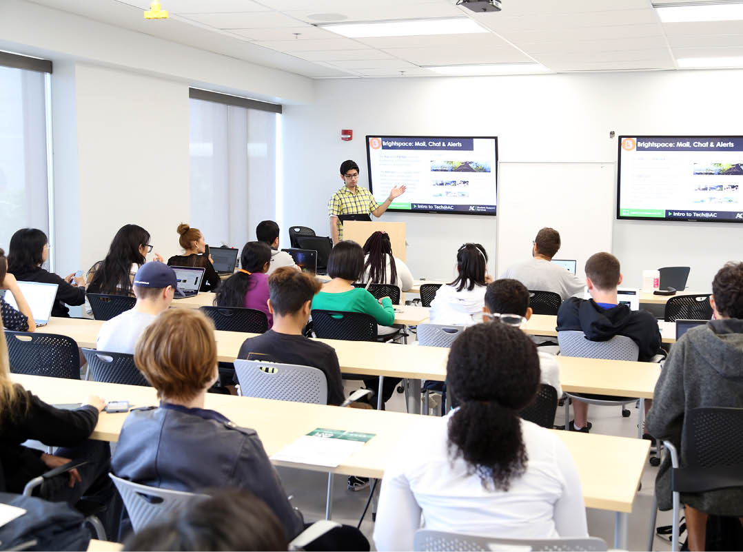 Photo of students sitting in a classroom workshop learning about Brightspace from an instructor. 