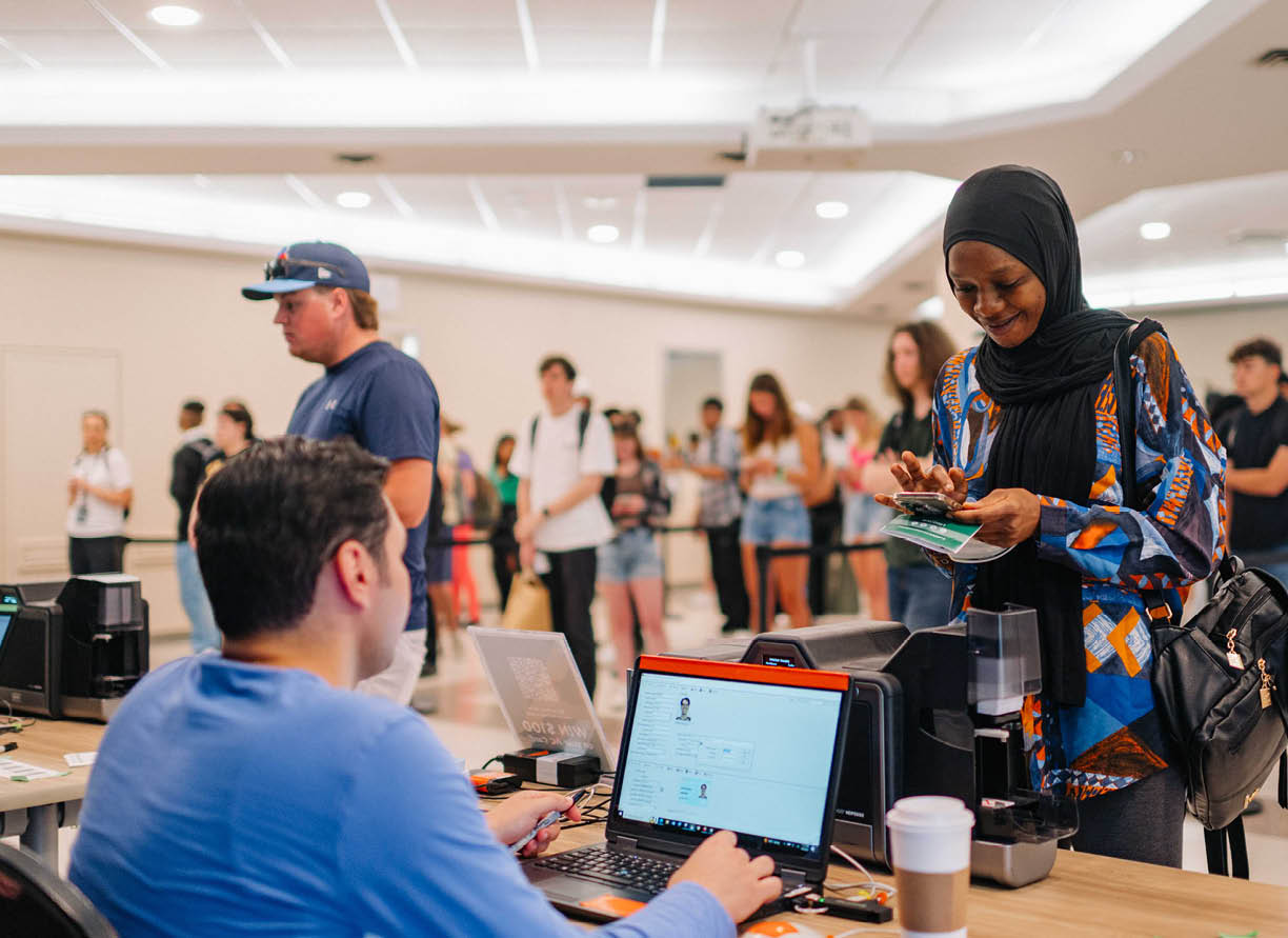 Photo of a student picking up their AC Card from Card Services employees. 