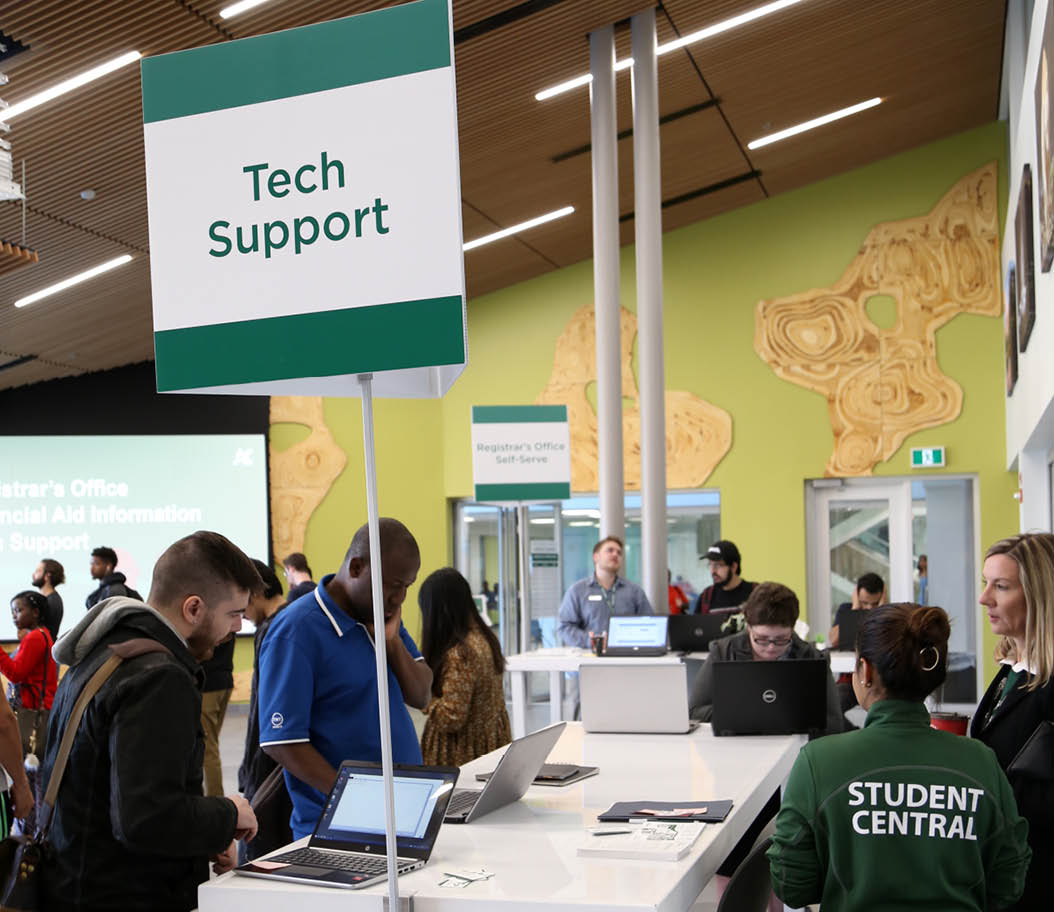 Photo of a tech support table on campus with students getting help. 