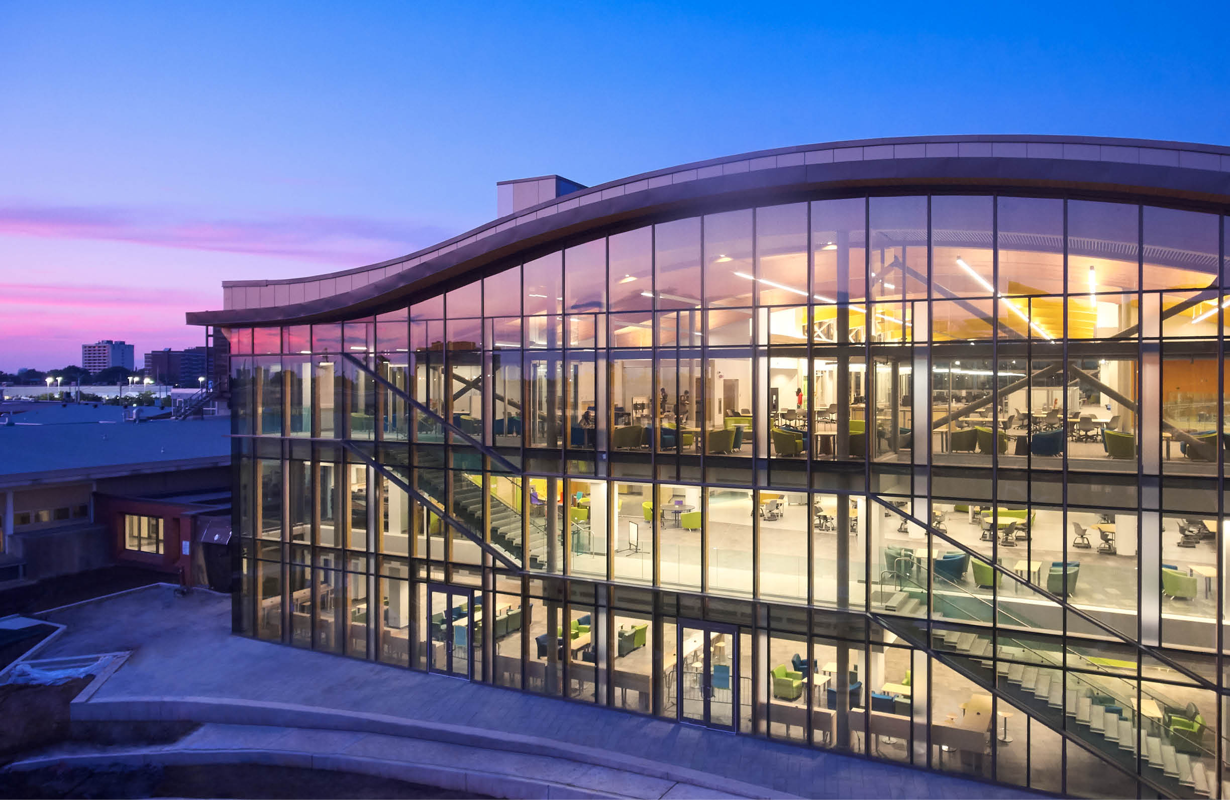 Photo of the DARE District buidling from the outside with lights shinging out in the evening light. 