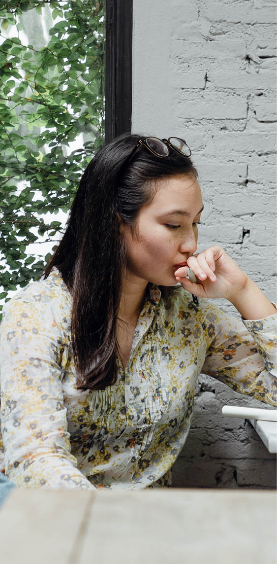 Photo of a student sitting and looking seriously at their page with their glasses pushed up on their head. 