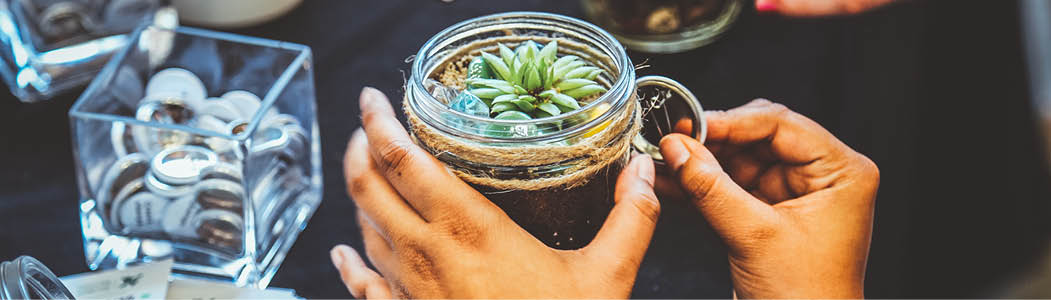 Close-up photo of a students hands putting the final touches on their DIY workshop mini terrarium. 
