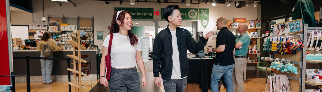Photo inside Connections the Campus Store, as a student is looking at a sweater they picked up. 