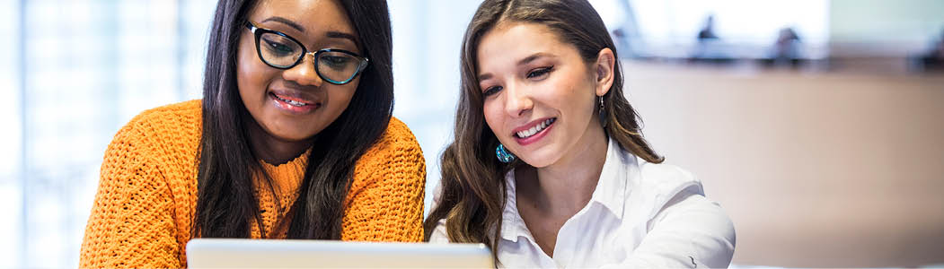 Smiling professional helping a student at a laptop.