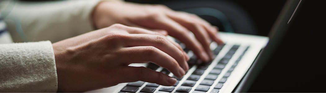 Close-up photo of hands on a laptop.
