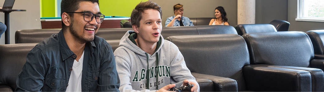 Students playing video games in the shared space at the Residence at the Ottawa Campus.