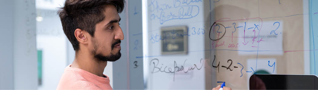 Student working on a problem on the glass walls at the SLC at the Ottawa campus.