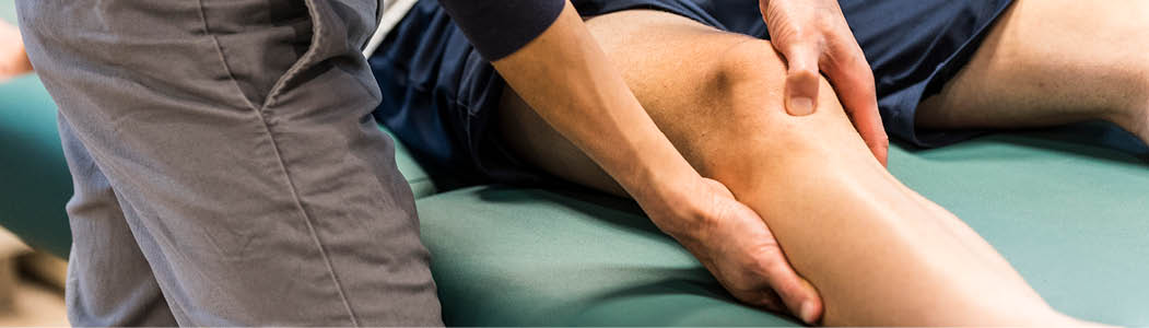 Close-up photo of a person massaging a students leg.