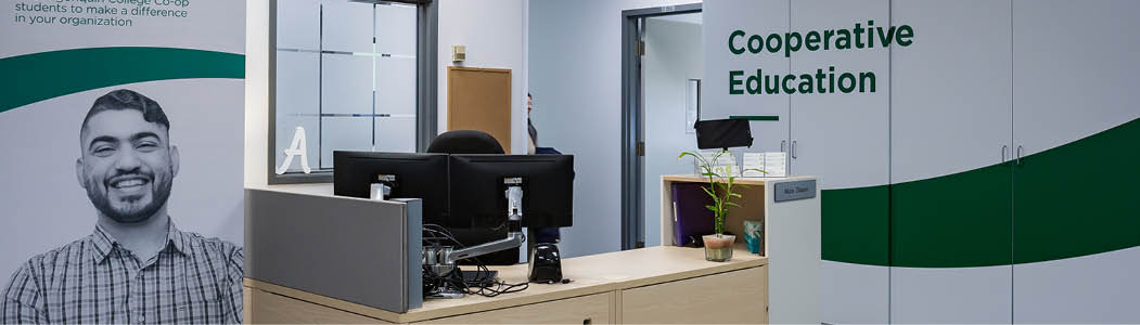 Smiling professional helping a student at a laptop.