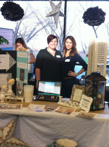 Two female business students posing in front of their trade show booth - student experience