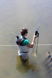 E-Tech student takes reading on water sample near culvert