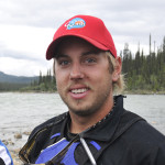 Grad Success Stories - outdoor adventure alumni with red hat by river