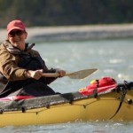 Outdoor Adventure graduate Joanne Smith - dressed in hat and coat in yellow kayak on water - Grad Success Stories