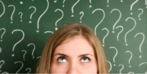 Student in front of blackboard with question marks 