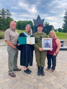 Wearing her Algonquin College convocation gown, Marcie Lane stands with her Father, Harry Lane; daughter Olivia Vernelli; and Mother, Bonnie Farrell at the Fallen Soldier Monument at Garrison Petawawa on Sunday, June 26.