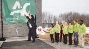 Fred Blackstein slams a champagne bottle against the Waterfront Campus as he helps christen the building in 2012.