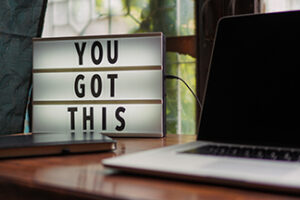 Photo of a sign saying "You Got This" - next to a laptop computer on a wooden desk.