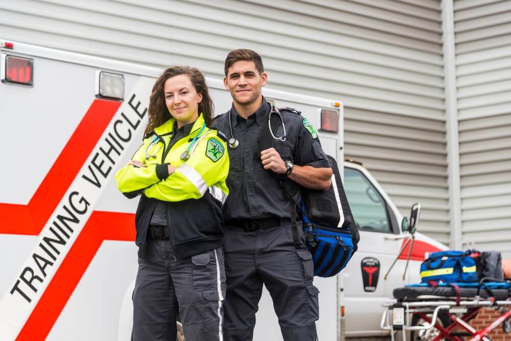Two paramedic students standing in front of the paramedic training vehicle
