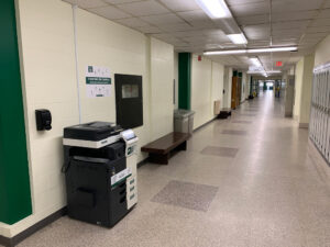 Image of a Konica Minolta black and white printer on the first floor of A building in the hallway next to room A137.