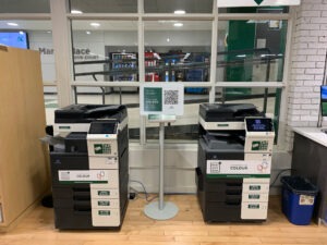 Image of two Konica Minolta colour printers on the first floor of H building located within Connections: The Campus Store room H110.