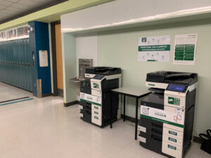 Image of one black and white Konica Minolta printer and one colour Konica Minolta printer on the second floor of N building in the hallway outside of room N208.
