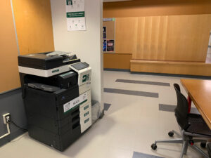 Image of a Konica Minolta black and white printer on the first floor of T building located in the study nook next to room T117.