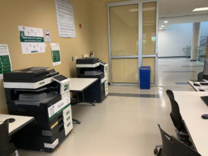Image of one black and white and one colour Konica Minolta printers located on the second floor of T building in the access lab in room T201.