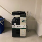Image of a Konica Minolta black and white printer on the second floor of the Pembroke campus located inside room 213.