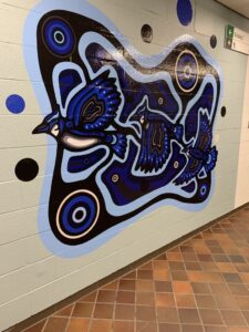 Indigenous design of a blue jay on a mural wall