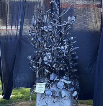 metal sculpture includes corn stalks, been shoots, squash, tobacco leaves and five small pairs of children's moccasins