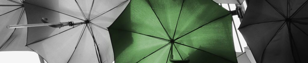 black and white umbrellas with one green umbrella in the middle.