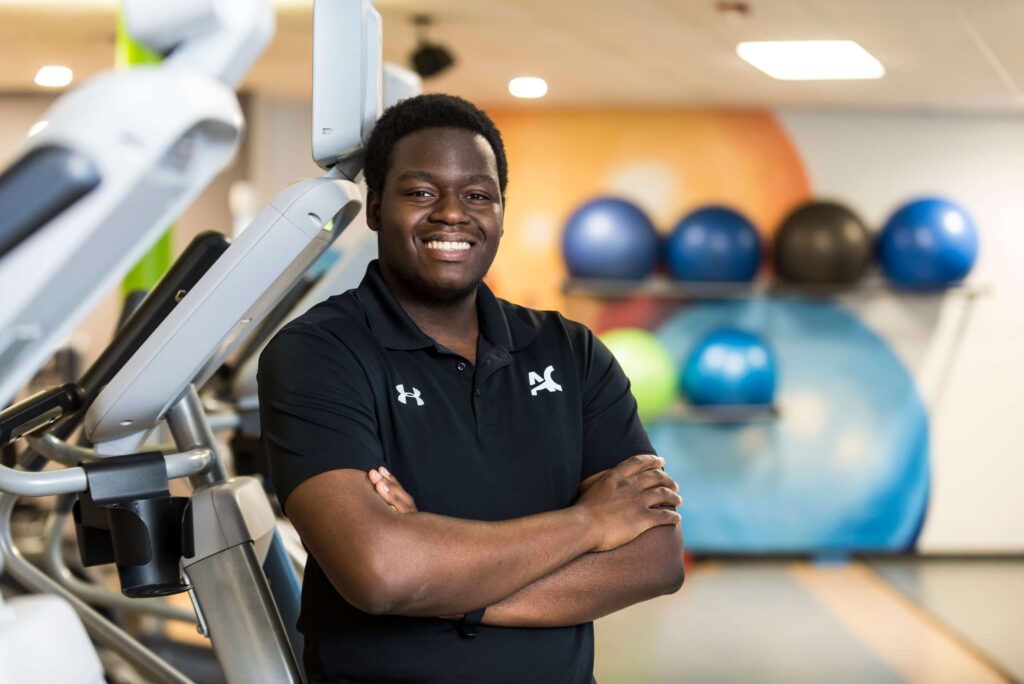 student standing by fitness equipment in fitness zone